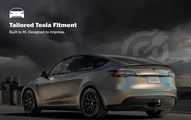 Rear-side view of a Tesla Model Y with an iridescent wrap parked on a rooftop, set against a dramatic cloudy sky with the text “Tailored Tesla Fitment” promoting custom vehicle styling.