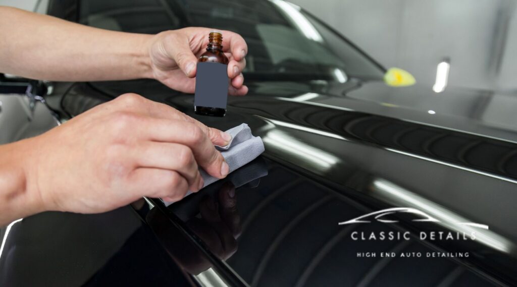 Technician applying professional ceramic coating to a black car surface using an applicator pad at Classic Details Auto Spa.