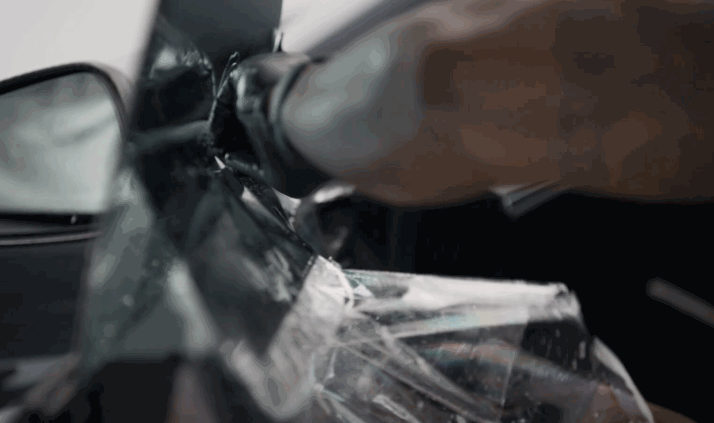 A technician works near the side mirror while installing window tint on a Tesla window. The wet film is being shaped along the glass edge for a precise finish.